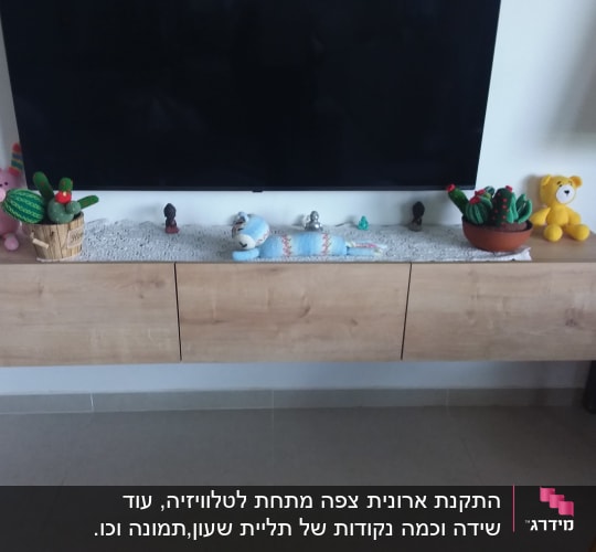ארונית עץ תלויה על הקיר מתחת לטלוויזיה